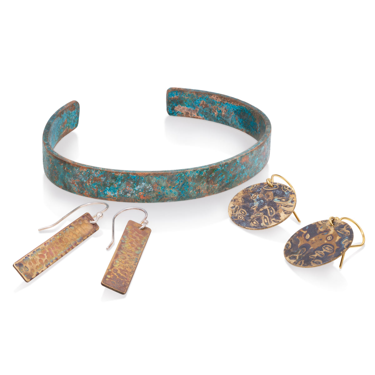 Patinated copper and brass jewelry featuring a cuff bracelet, rectangular earrings, and disc earrings