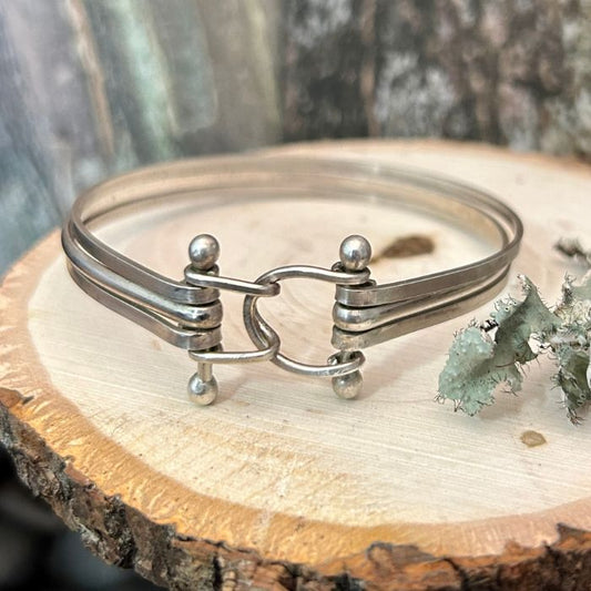 Silver bracelet on a wooden surface with a natural background