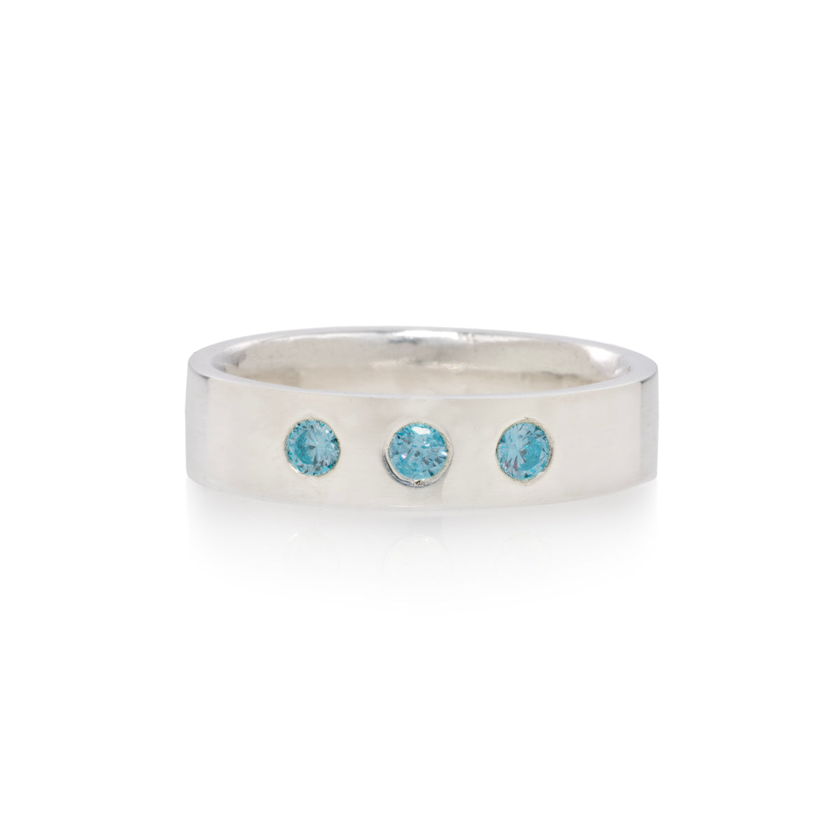 A silver band ring featuring three small, round-cut light blue gemstones set in a row, photographed on a clean white background.