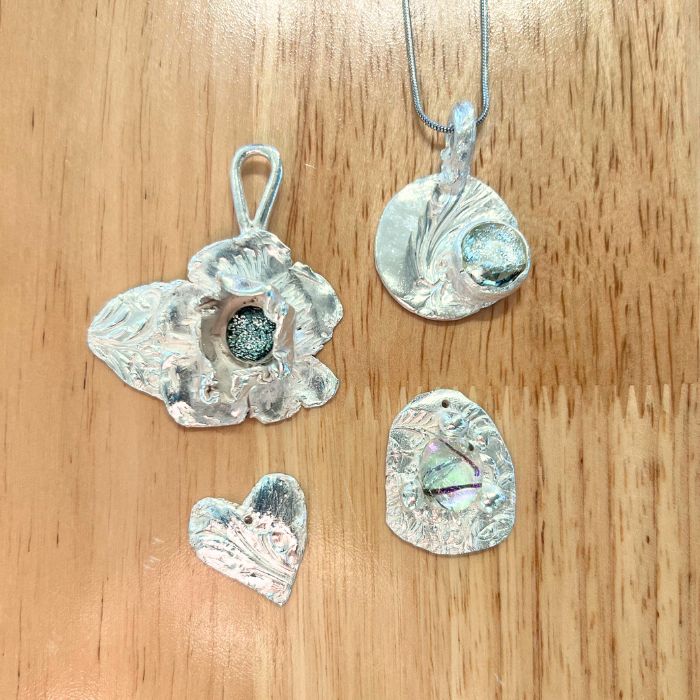 Set of PMC silver pendants on a wooden surface