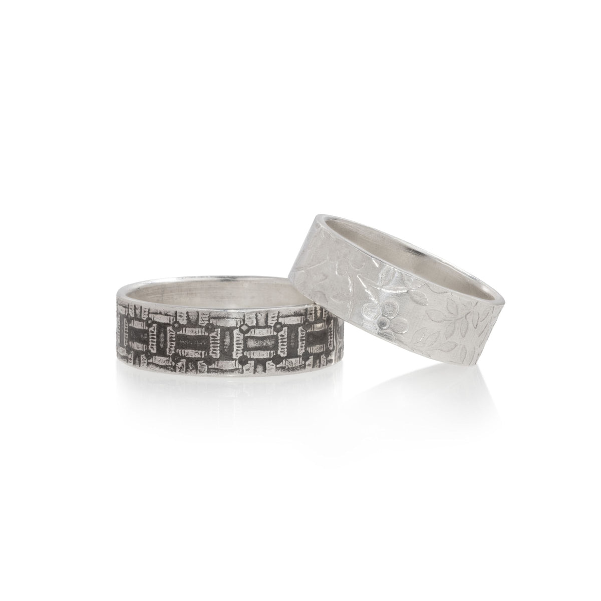 Two silver rings on a white background, one with a detailed chain-link pattern and the other with a textured floral design.