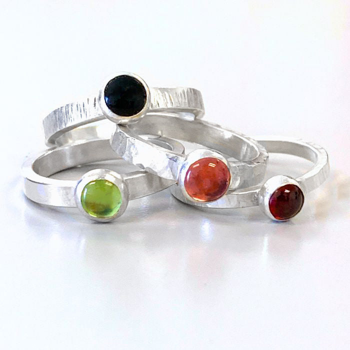 Set of silver rings with colored gemstones on a white background