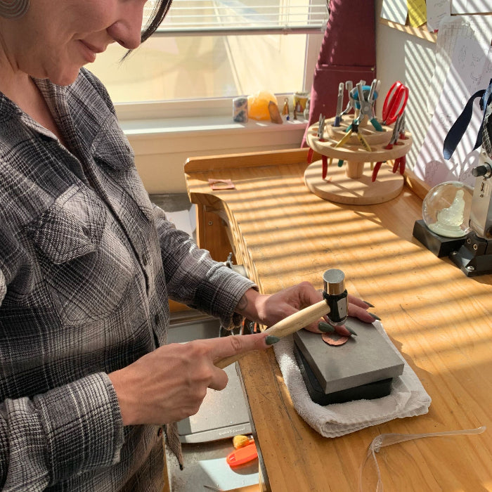 Student hammering copper pendant